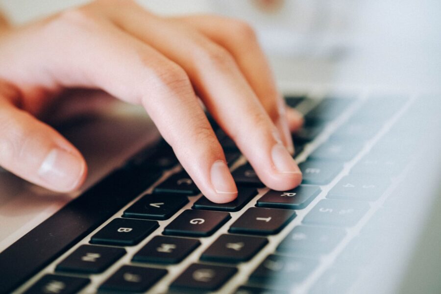 Close-up of hands typing on a laptop keyboard while setting up an online dropshipping store