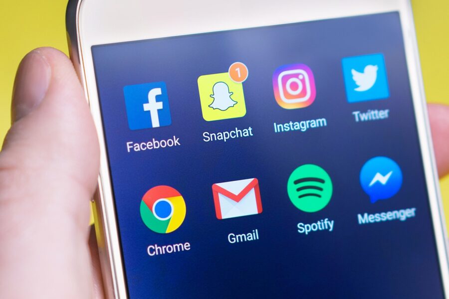 Hand holding a smartphone showing social media app icons used to build a business presence online