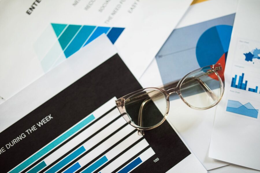 Printed infographics with bar and pie charts beside glasses, showing data visualization used in marketing