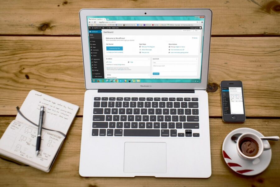 Laptop showing a blog dashboard beside a notebook and coffee while planning a blog content strategy