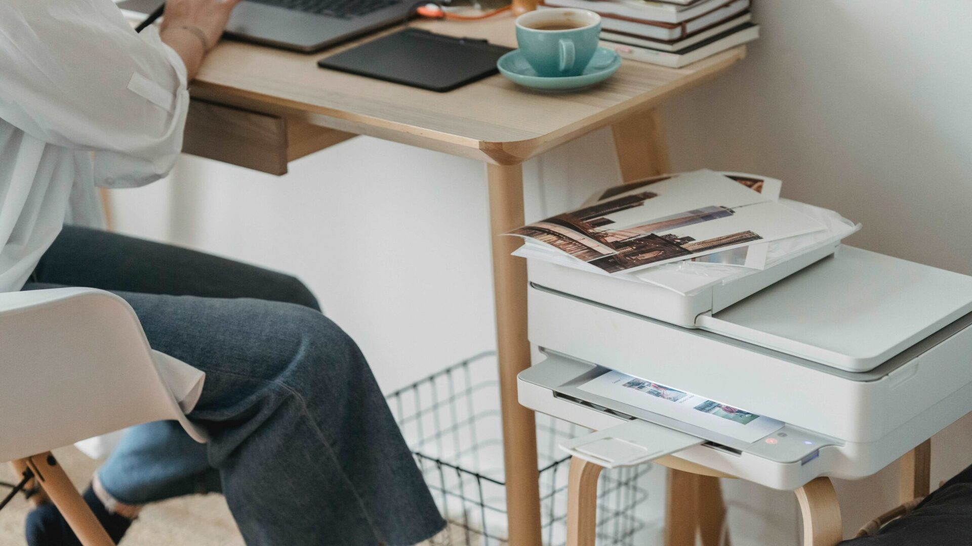 Artist at a desk beside a printer producing photo prints while preparing digital artwork for printing