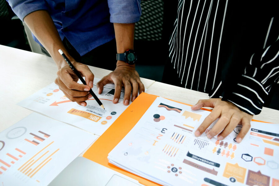 Two people reviewing printed analytics charts and performance reports to guide business decisions