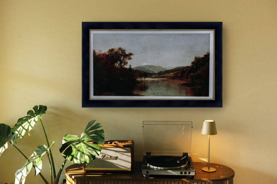 Framed landscape artwork displayed above a record player, lamp, and indoor plants in a modern living room
