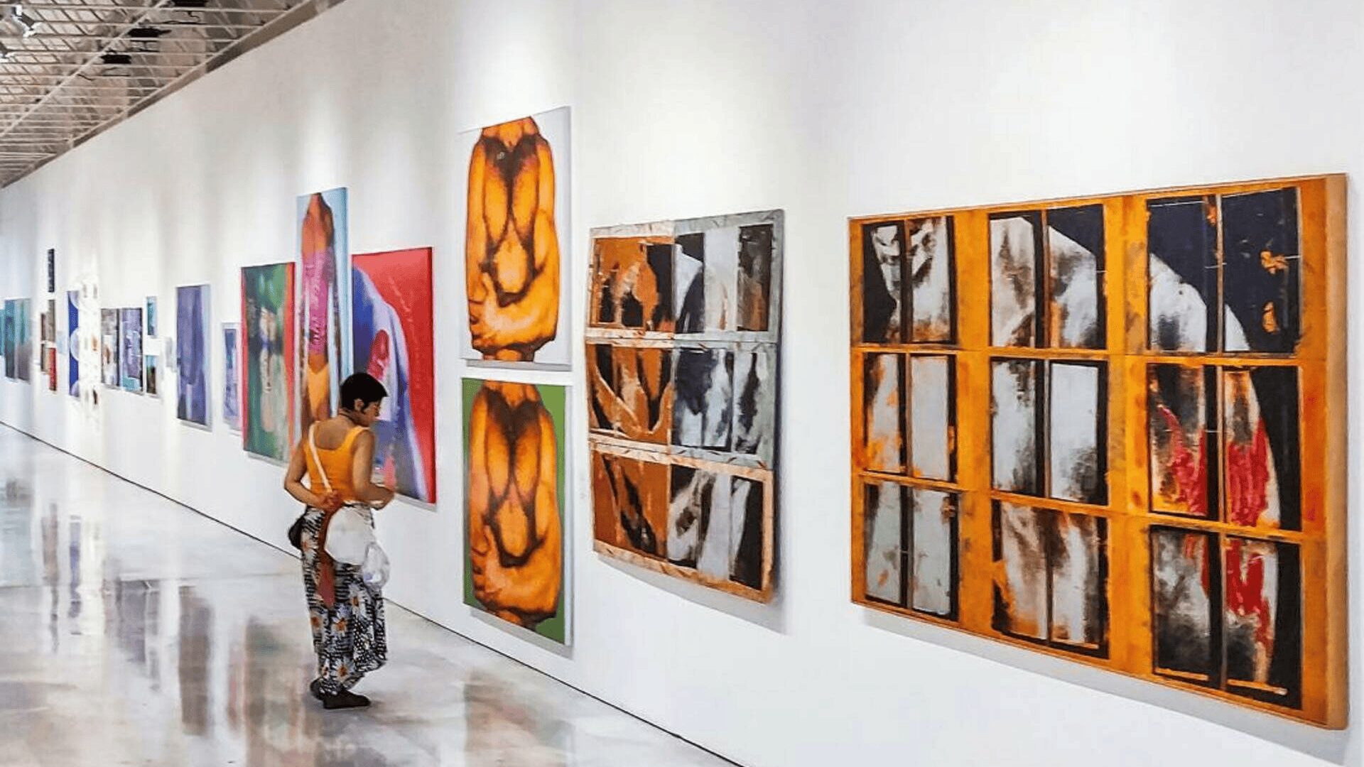 Visitor viewing large contemporary abstract paintings displayed in a modern art gallery