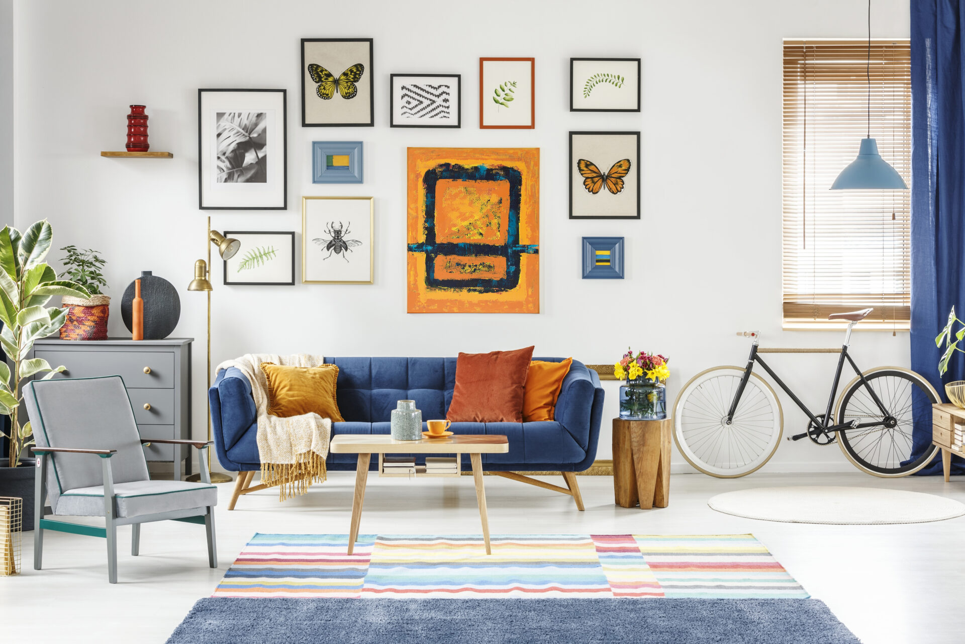 Colorful gallery wall of framed artwork displayed above a blue sofa in a modern living room