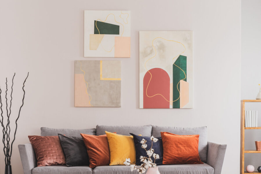 Abstract canvas prints in green, red, and yellow tones above a gray sofa showing color psychology in wall art