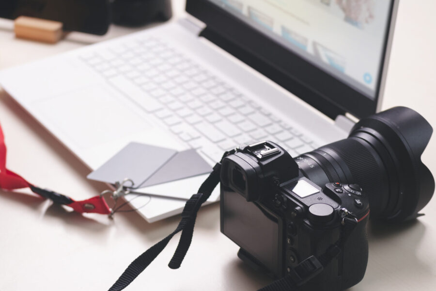 DSLR camera beside a laptop on a photographer's desk used to sell photography prints online