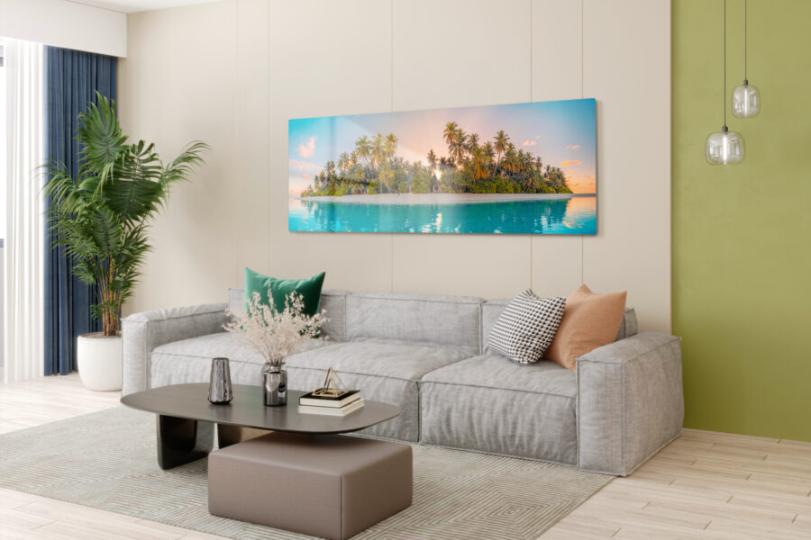Panoramic metal photo print of a tropical island at sunset hung above a gray sofa in a modern living room