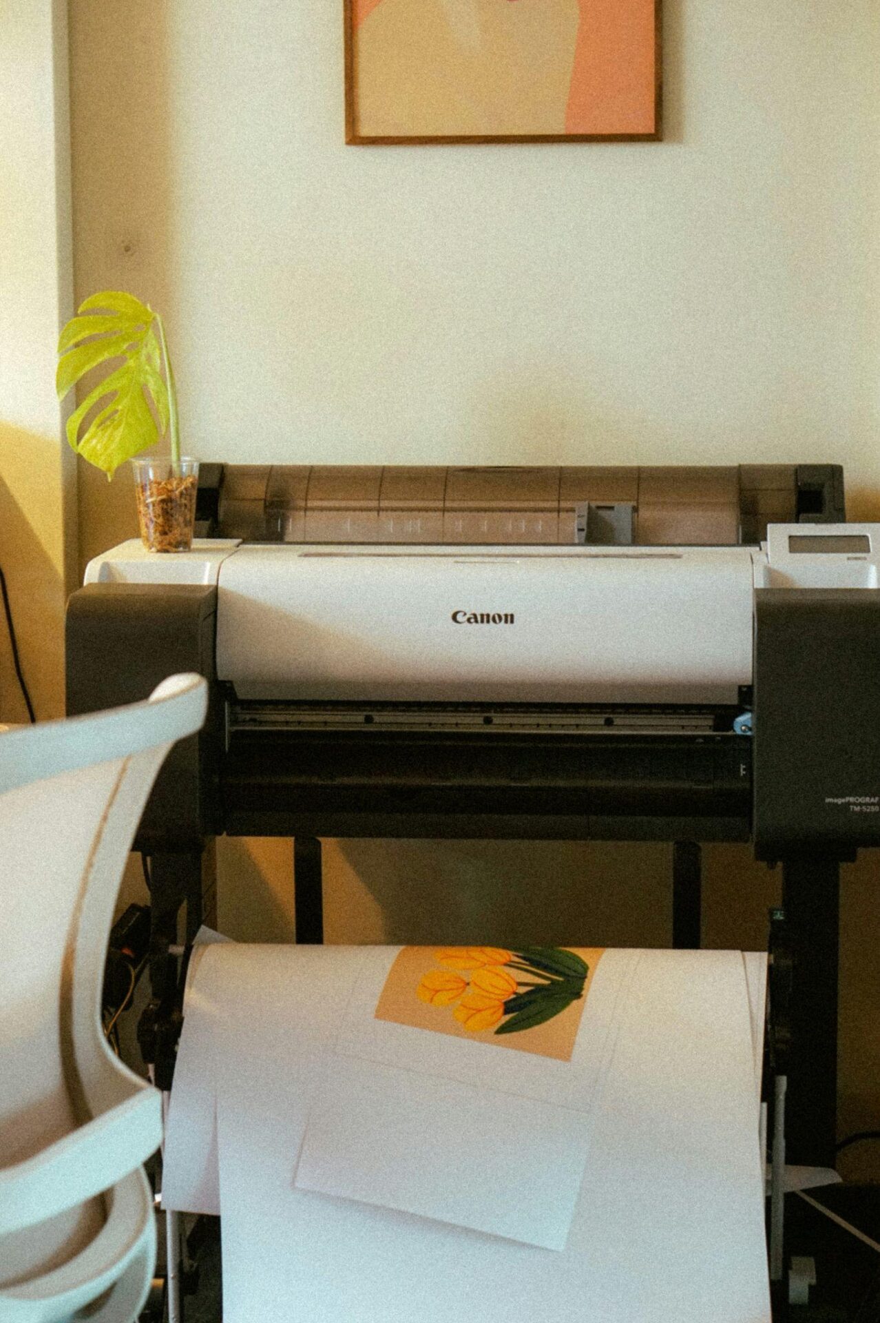 Large-format printer with a yellow tulip art print on white paper in a studio